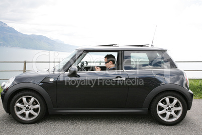 Young man in his fancy car chatting with his device up the hills