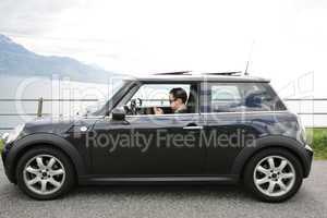 Young man in his fancy car chatting with his device up the hills