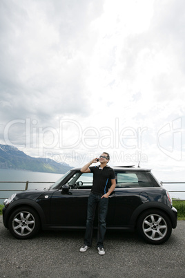 Young man talking happy out of his car in the hills