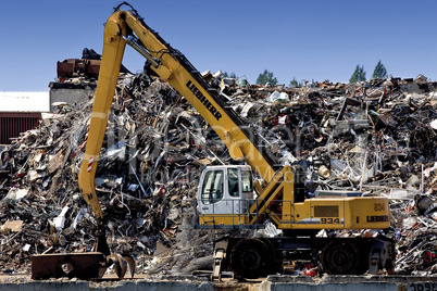 Mechanical digger in front of a waste