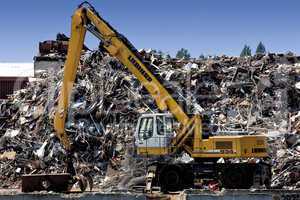 Mechanical digger in front of a waste