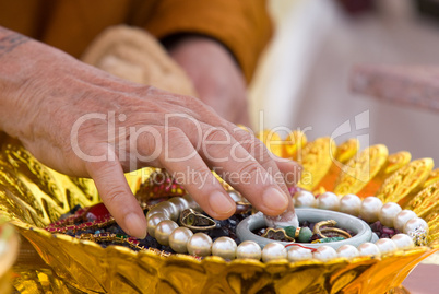 Hand of Buddhist monk painting religious symbols on amulets with his finger. Shallow depth of field.