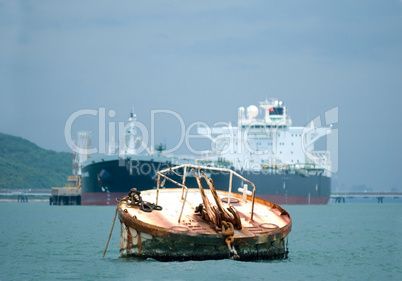 Rusty mooring buoy with oil-tanker