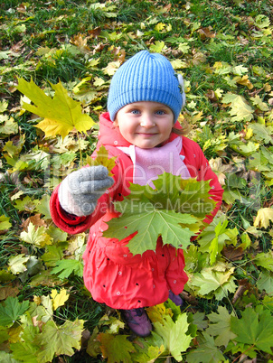 The little girl with yellow leaf in autumn