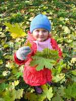 The little girl with yellow leaf in autumn