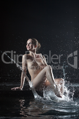 Beautiful nude young woman near water