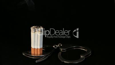 smoldering cigarette in handcuffs on black background, Timelapse