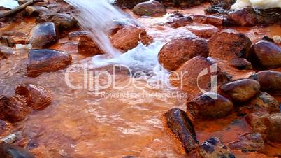 Mineral water with iron flows over the rocks