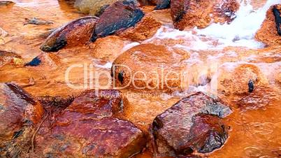 Mineral water with iron flows over the rocks