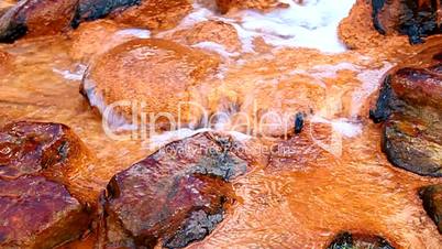 Mineral water with iron flows over the rocks