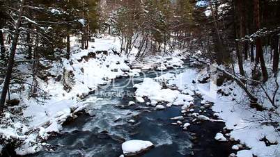 Pure blue mountain river flowing among the snow-covered shores