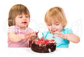Two little baby girl eating cake