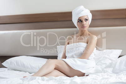 Sexy woman sitting on bed after bath in hotel room