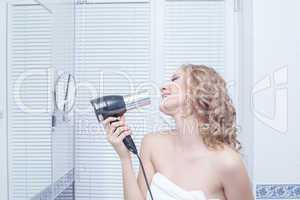 Happy young blonde woman singing in bathroom