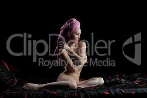 Pretty young woman sitting nude on bed