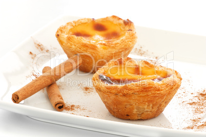 Custard Pies over a white plate with cinnamon sticks