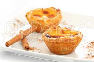 Custard Pies over a white plate with cinnamon sticks