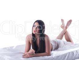 Beauty brunette woman lying on silk bed isolated