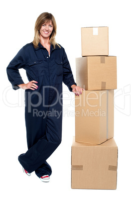 Beautiful delivery woman standing beside cartons