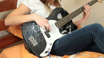 Young Girl Playing Bass Guitar At Home
