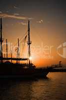Sailing ship silhouetted against amber setting sun