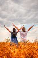 Couple staying with raised hands at a wheat field