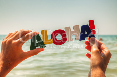 Female's hand holding colorful word 'Aloha'