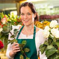 Smiling florist cutting rose flower shop woman