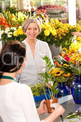 Senior woman buying plant paying flower market