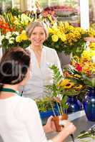 Senior woman buying plant paying flower market