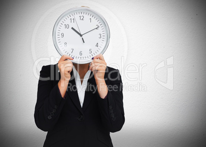 Businesswoman hiding face with clock