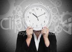 Businesswoman hiding her face with clock
