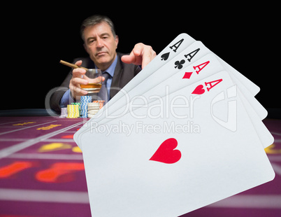 Gambler holding whiskey at poker table with digital hand of card