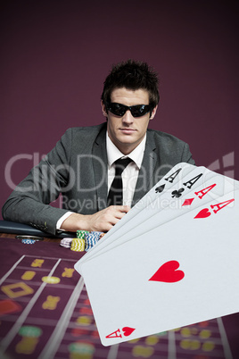 Gambler in sunglasses with digital four aces in foreground