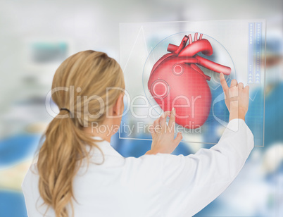 Blonde doctor consulting touchscreen displaying heart diagram