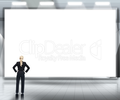 Businesswoman looking up at large blank screen under spotlights
