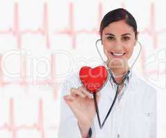 Doctor holding stethoscope up to red heart graphic