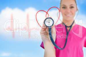 Happy nurse holding up stethoscope to heart design