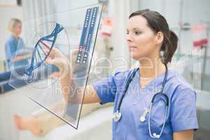 Nurse touching screen showing blue DNA helix data