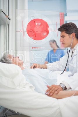 Doctor checking pulse of elderly patient beside screen displayin