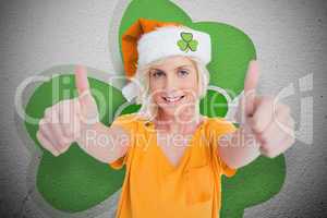 Girl in orange t-shirt giving thumbs up on shamrock background