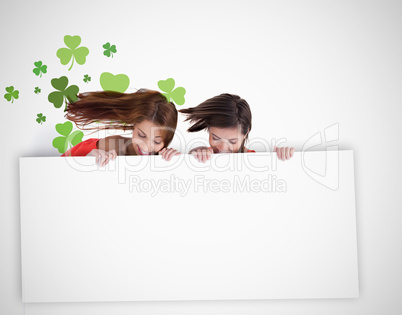 Girls looking down at blank placard with shamrock background