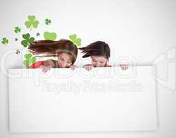 Girls looking down at blank placard with shamrock background