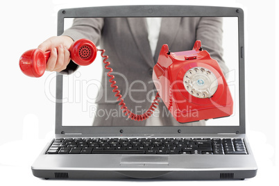 Businesswoman reaching out from laptop handing phone receiver