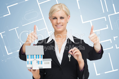 Multi-tasking estate agent holding keys and model home while giv