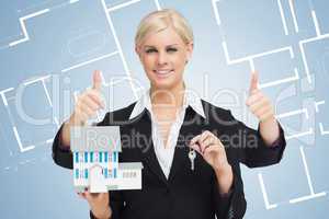 Multi-tasking estate agent holding keys and model home while giv