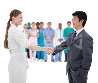 Business people shaking hands with medical staff in background