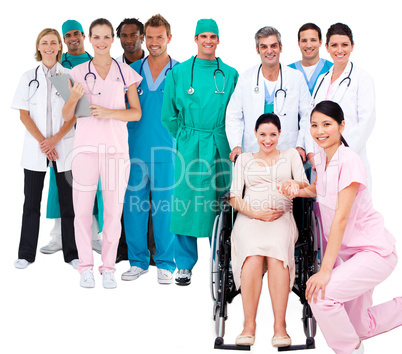 Nurse with pregnant woman in wheelchair with medical staff