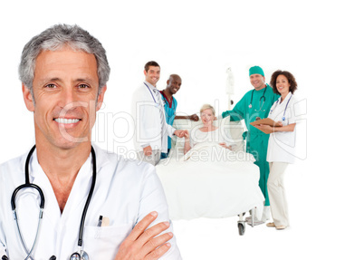 Smiling doctor with patient in bed and medical staff behind him