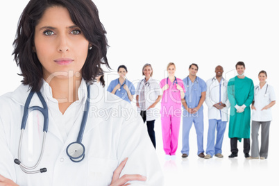 Woman doctor standing arms crossed in front of her team